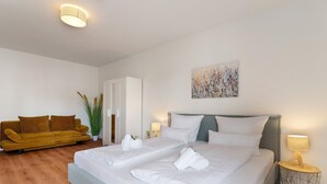 A bedroom with a bed, two bedside tables, a nightstand, a sofa, and a potted plant. - Holiday Apartment "Km Style 5" with Balcony & Wi-Fi (Freiburg im Breisgau)