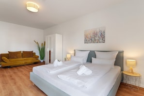 Ein Schlafzimmer mit einem Bett, zwei Nachttischen, einem Sofa und einer Zimmerpflanze.
