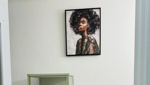 Un baño con un armario verde que contiene toallas enrolladas, una pequeña planta en maceta y una obra de arte enmarcada en la pared.