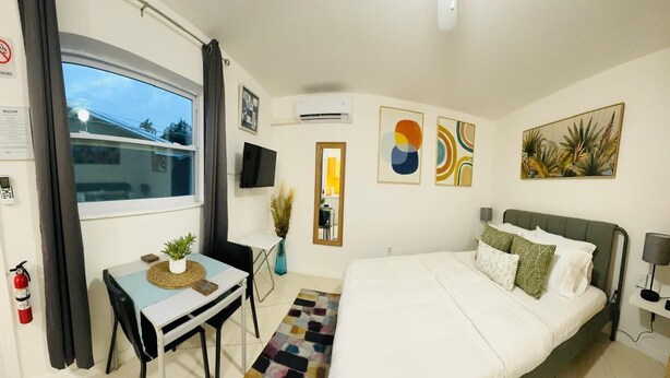 Una habitación de hotel con cama, escritorio, silla, televisor y ventana.