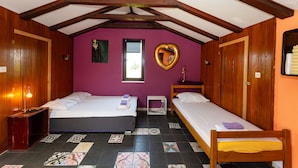 Een kamer met twee bedden, houten balken, een paarse wand, een spiegel in de vorm van een hart en een raam.