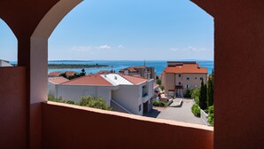 A view through an archway of a coastal area with buildings and a clear sky. - Comfortable apartments Malina B4 br 4 (Novalja)