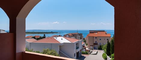 A view through an archway of a coastal area with buildings and a clear sky.