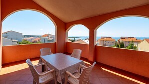 A balcony with a table and chairs, a view of the sea, and buildings in the background. - Comfortable apartments Malina A4 br 3 (Novalja)