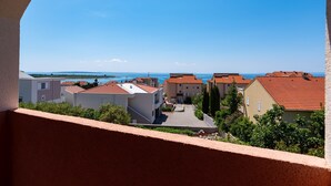 A coastal residential area with buildings, a clear sky, and a view of the sea. - Comfortable apartments Malina A4 br 3 (Novalja)
