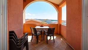 A balcony with a table and chairs, a potted plant, and a view of buildings. - Comfortable apartments Malina C6 br 8 (Novalja)