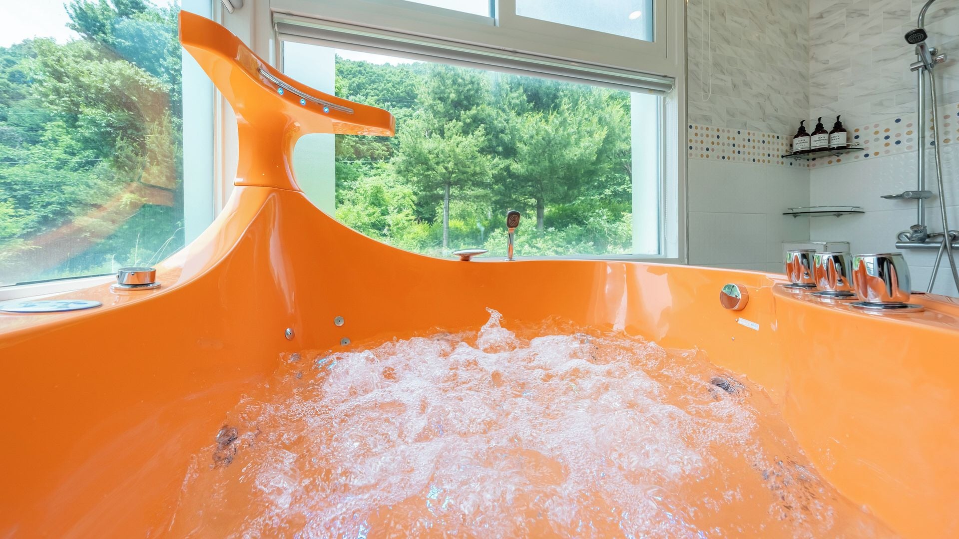 A bathtub with a view of a forest through a window.