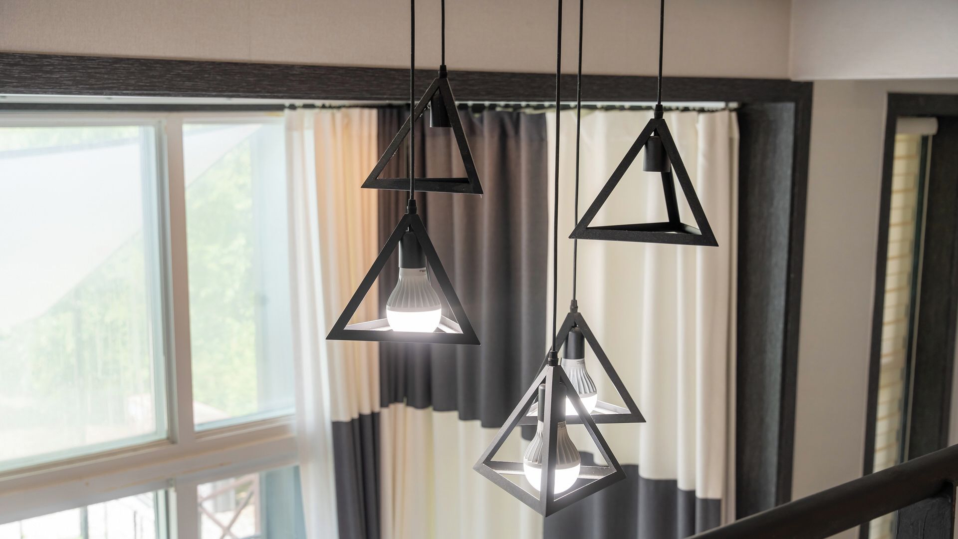 Una habitación con ventana, cortinas y tres lámparas colgantes.