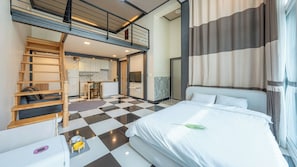 Une chambre d’hôtel comprenant un lit, un bureau, une chaise, un canapé, un coin repas et un escalier.