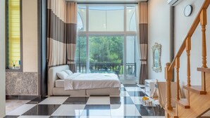 A bedroom with a large window, a bed, a checkered floor, a staircase, and a view of greenery outside. - Gapyeong Chagall Spa Pension (Gapyeong)