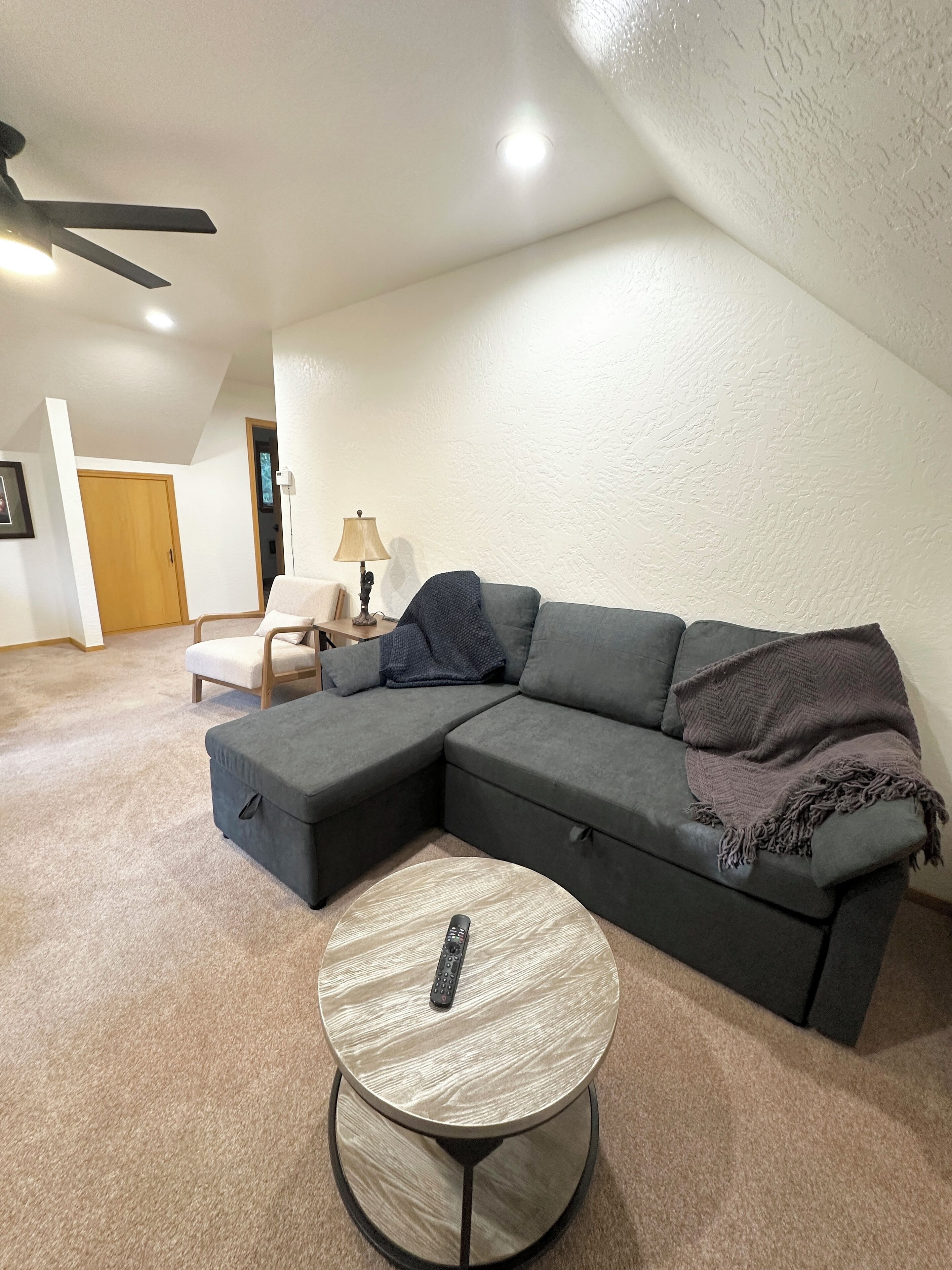 A living room with a sectional sofa, a round coffee table, and a ceiling fan.