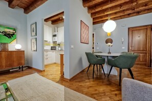 Un coin repas avec une table et des chaises, des poutres en bois au plafond et des œuvres d’art encadrées aux murs.