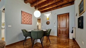 Een eethoek met een houten plafond, een ronde tafel met vier stoelen en een hanglamp.