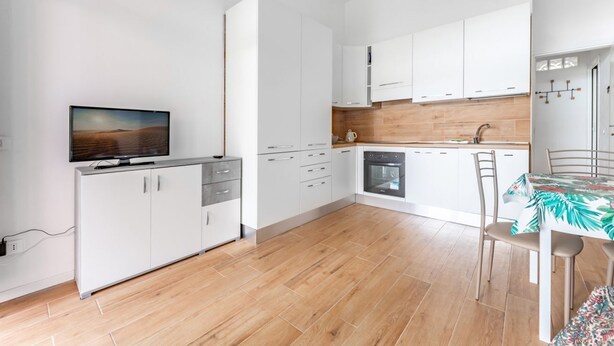 Una cocina moderna con armarios blancos, encimera de madera y una zona de comedor con mesa y sillas.