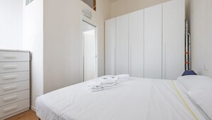 Un dormitorio con cama, armario y escritorio.