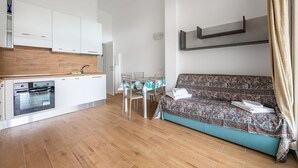 Una cocina moderna con armarios blancos, horno empotrado y comedor con mesa y sillas.