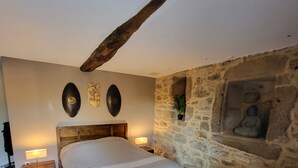 A bedroom with a wooden bed, stone walls, and a stone fireplace. - Charm and serenity... (Parisot)