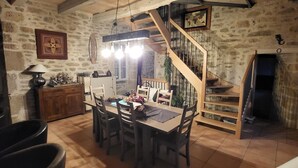 A rustic dining area with a wooden table and chairs, a chandelier, and a stone wall. - Charm and serenity... (Parisot)