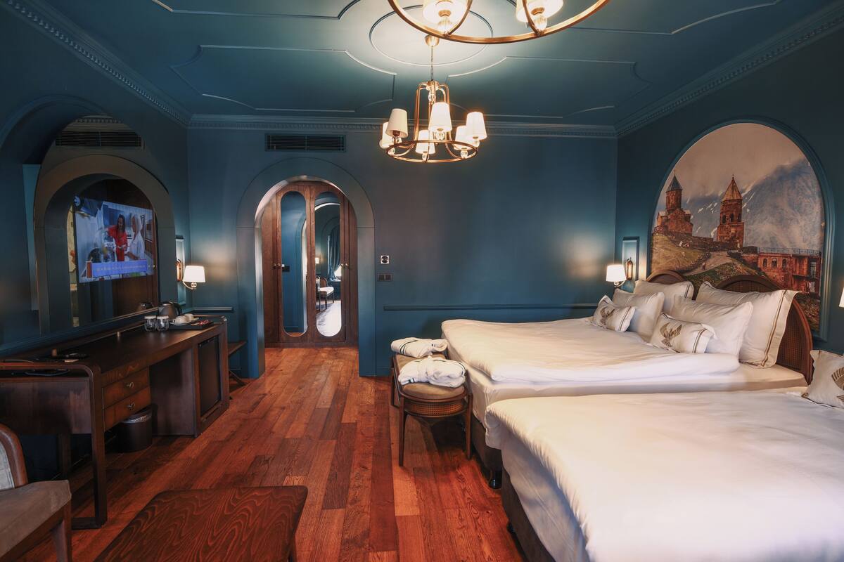 Una habitación de hotel con una cama grande, un escritorio y una televisión.