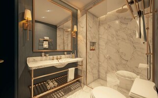Un baño moderno con tocador de mármol, un espejo grande, ducha a ras de suelo y un inodoro.
