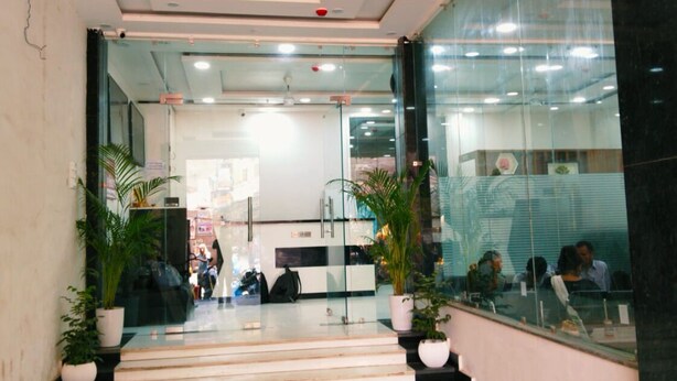Un espace d’accueil moderne avec des portes vitrées, un escalier et des plantes en pot.