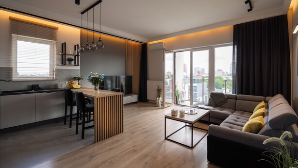 Ein moderner Wohnraum mit Küche, Essbereich und einer Couch mit Blick auf die Stadt.
