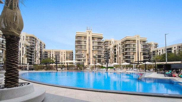 Una piscina rodeada de edificios residenciales de varios pisos con balcones.