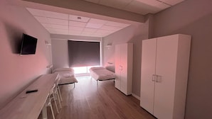 A room with two beds, a desk, and a TV. - Unicorn Residence for Students (Valencia)