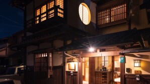 Un edificio japonés tradicional con fachada de madera, un amplio ventanal circular y una pequeña zona de entrada con escalones.