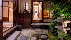 Un jardín japonés tradicional con un farol de piedra, senderos de piedra y arquitectura de madera.