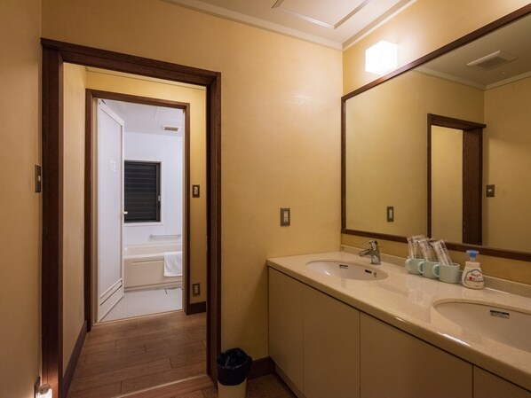 A hotel bathroom with a large mirror, two sinks, and toiletries on the counter.