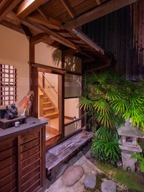 Ein traditioneller japanischer Eingangsbereich mit einer Holztür und einer kleinen Steintorlaterne.
