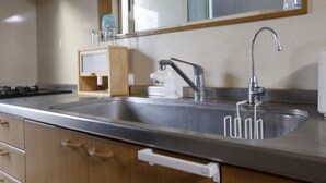 A kitchen with a stainless steel sink, wooden cabinets, and a window above the sink.