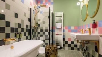 Ein Badezimmer mit einer weißen Badewanne, einem goldfarbenen Waschtisch und einer Dusche mit goldenem Wasserhahn.