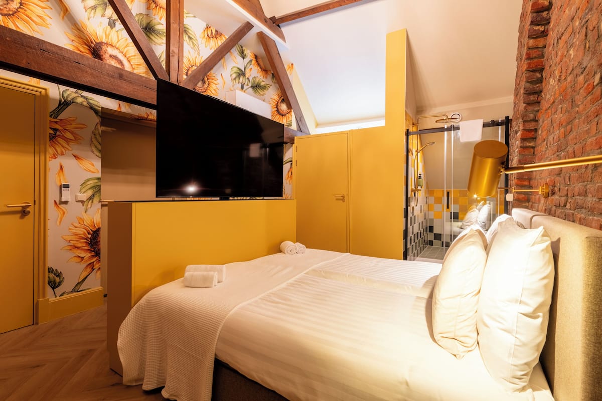 Un dormitorio con cama, televisión, ducha y pared de ladrillo.