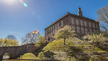 Un edifici històric amb una torre destacada, un pont i un riu.