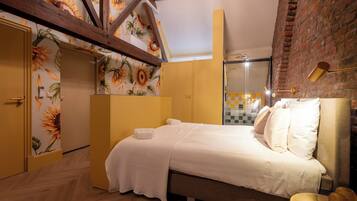 Ein Schlafzimmer mit Bett, Kleiderschrank, Spiegel und einer Ziegelwand.