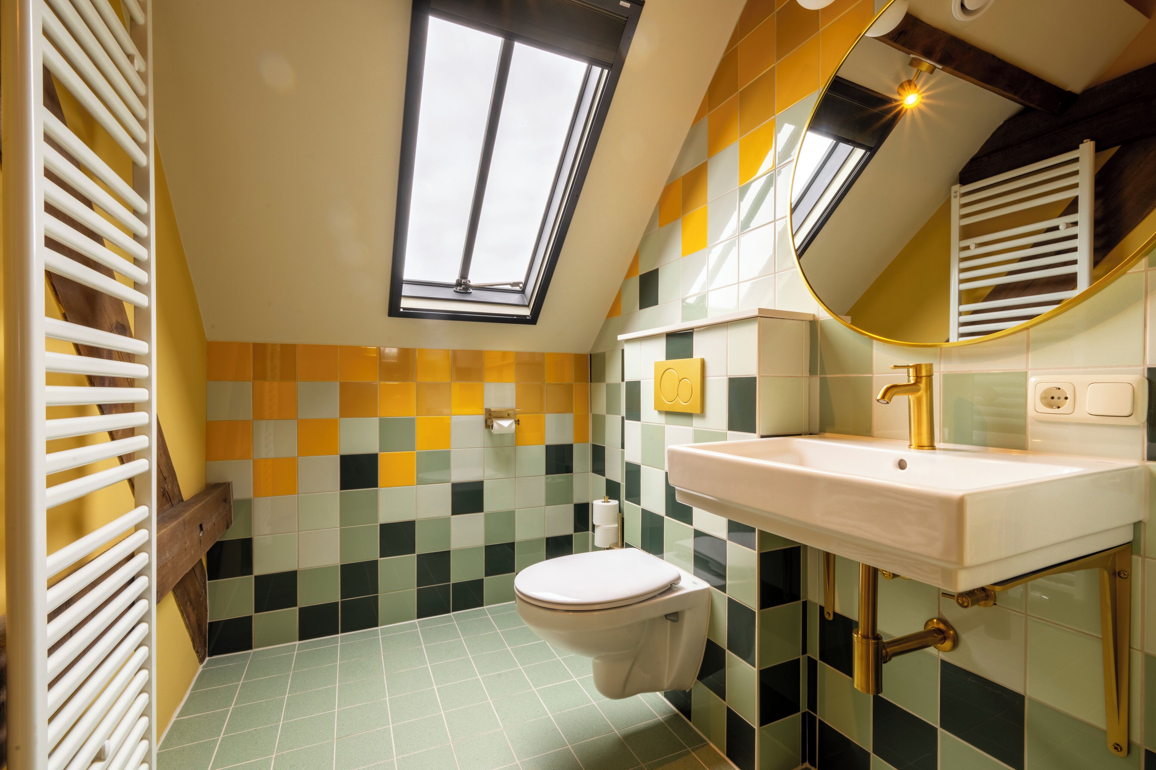 Een badkamer met dakraam, toilet, wastafel en spiegel.