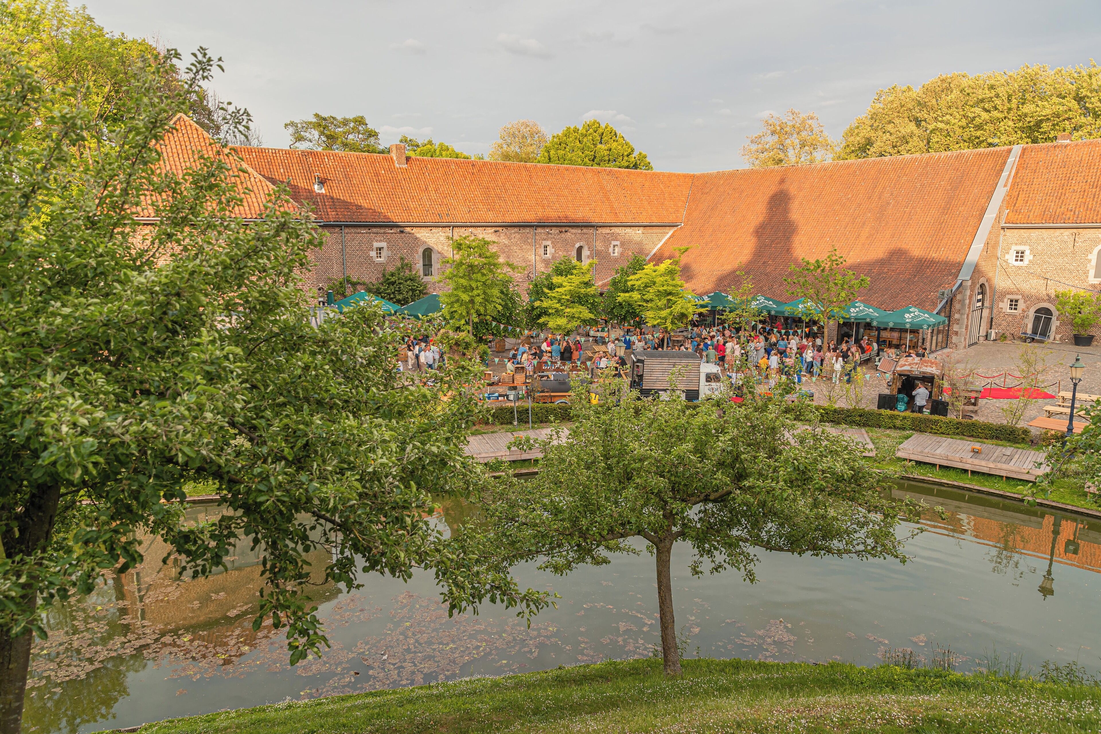 A courtyard with a pond, trees, and a crowd of people.