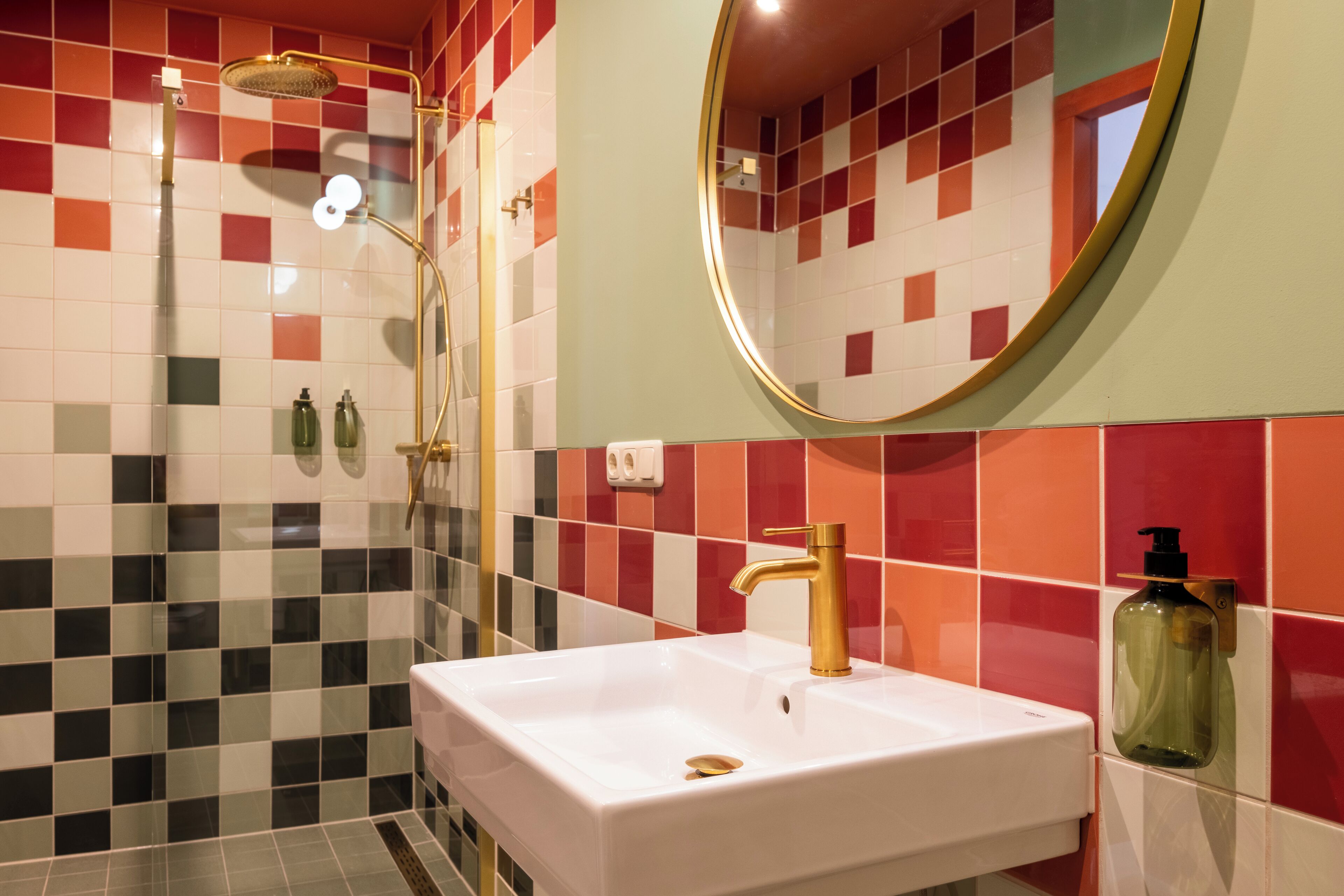 Een badkamer met een wit wastafelblad, een gouden kraan en een douche met een gouden douchekop.