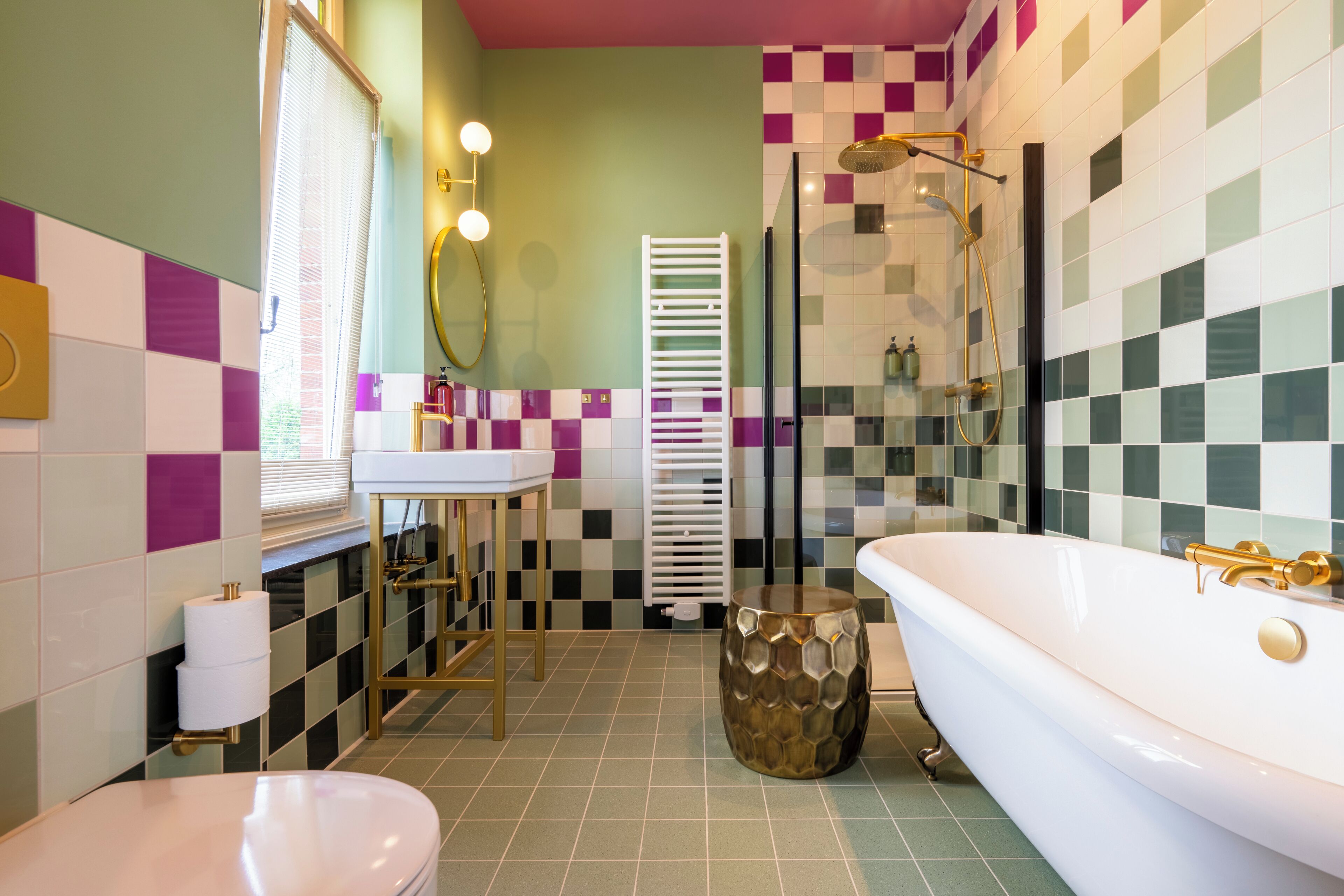 A bathroom with a white bathtub, a sink, a toilet, and a shower area.