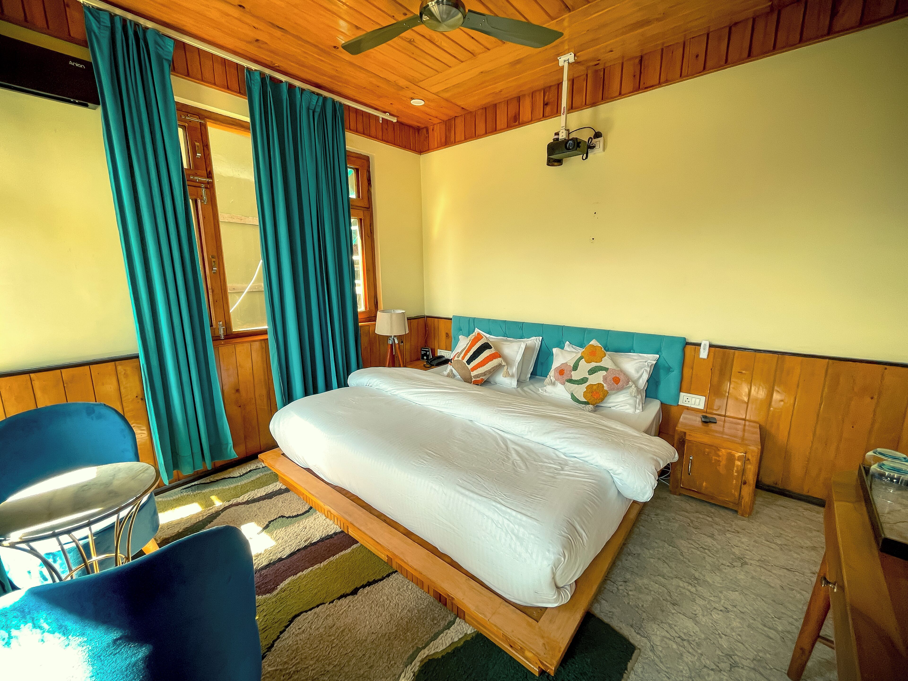 Ein ordentlich eingerichtetes Schlafzimmer mit einem Bett, einem Sessel, einem Nachttisch und einem Deckenventilator.