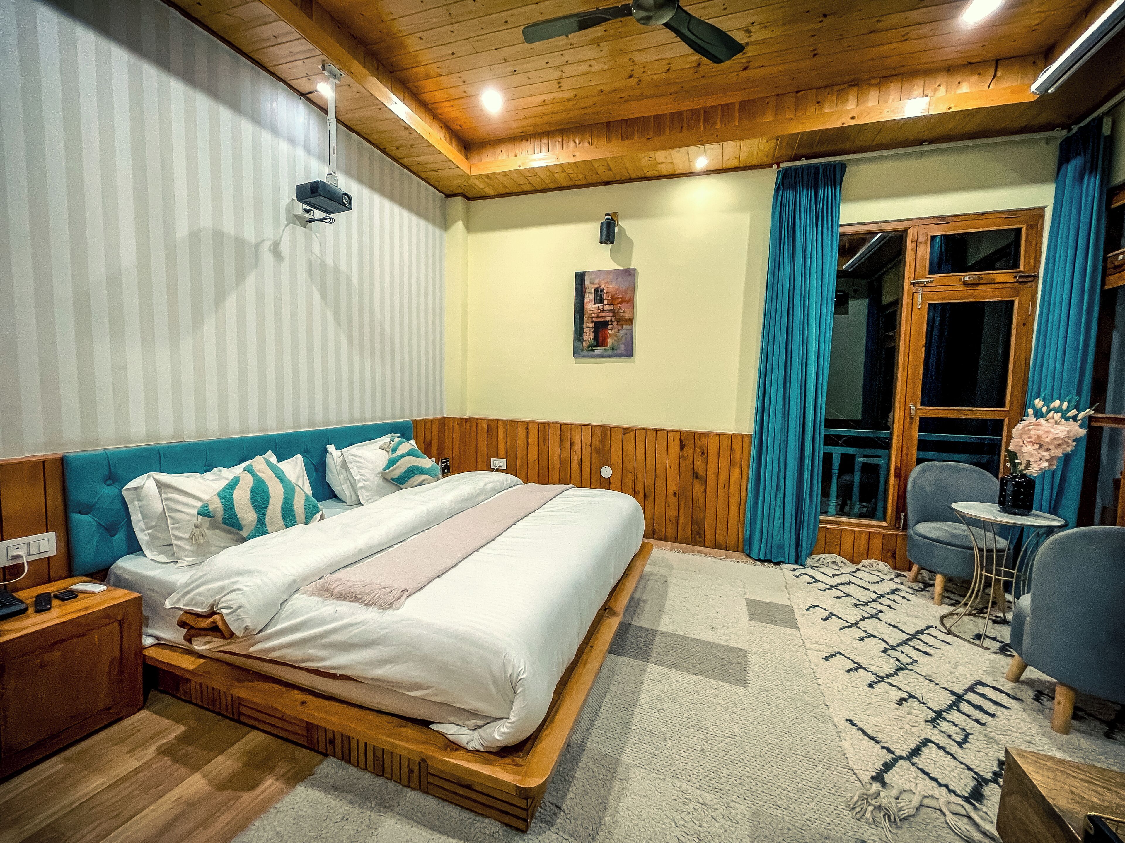 A bedroom with a wooden headboard, a bed with white bedding, a small bedside table, and a chair.