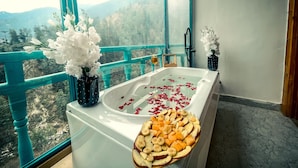 A bathroom with a bathtub, a bowl of fruit, and a vase of flowers. - The Elevia Hotels (Banjar)