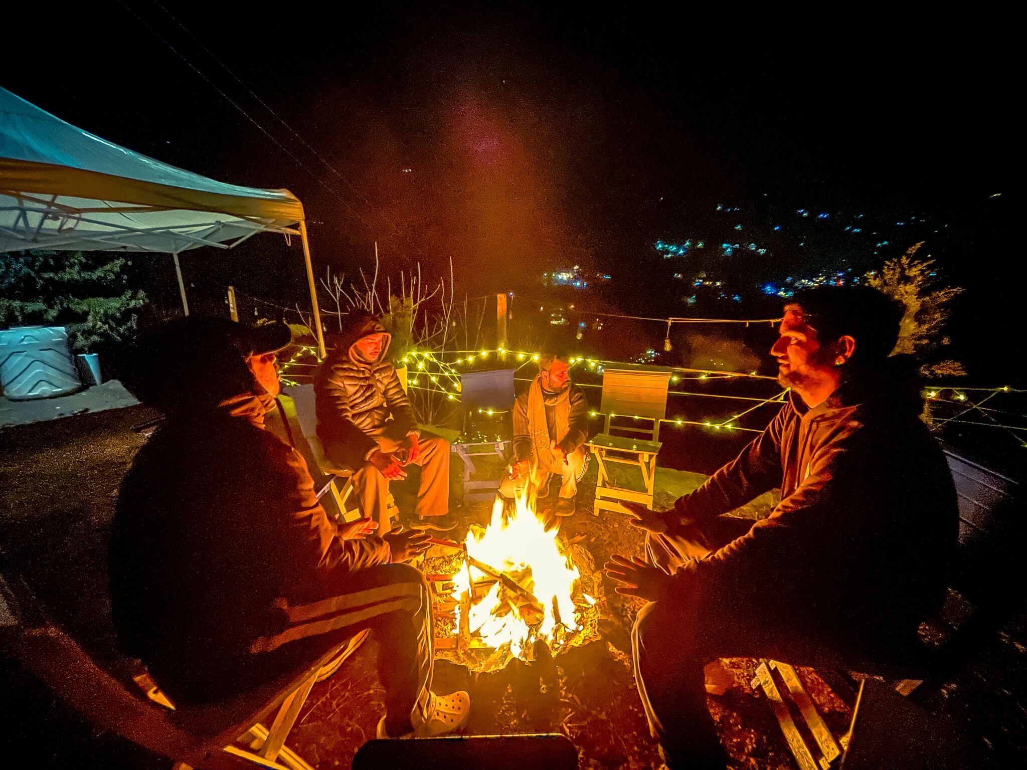 A group of people sitting around a campfire at night.