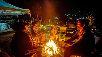 A group of people sitting around a campfire at night.
