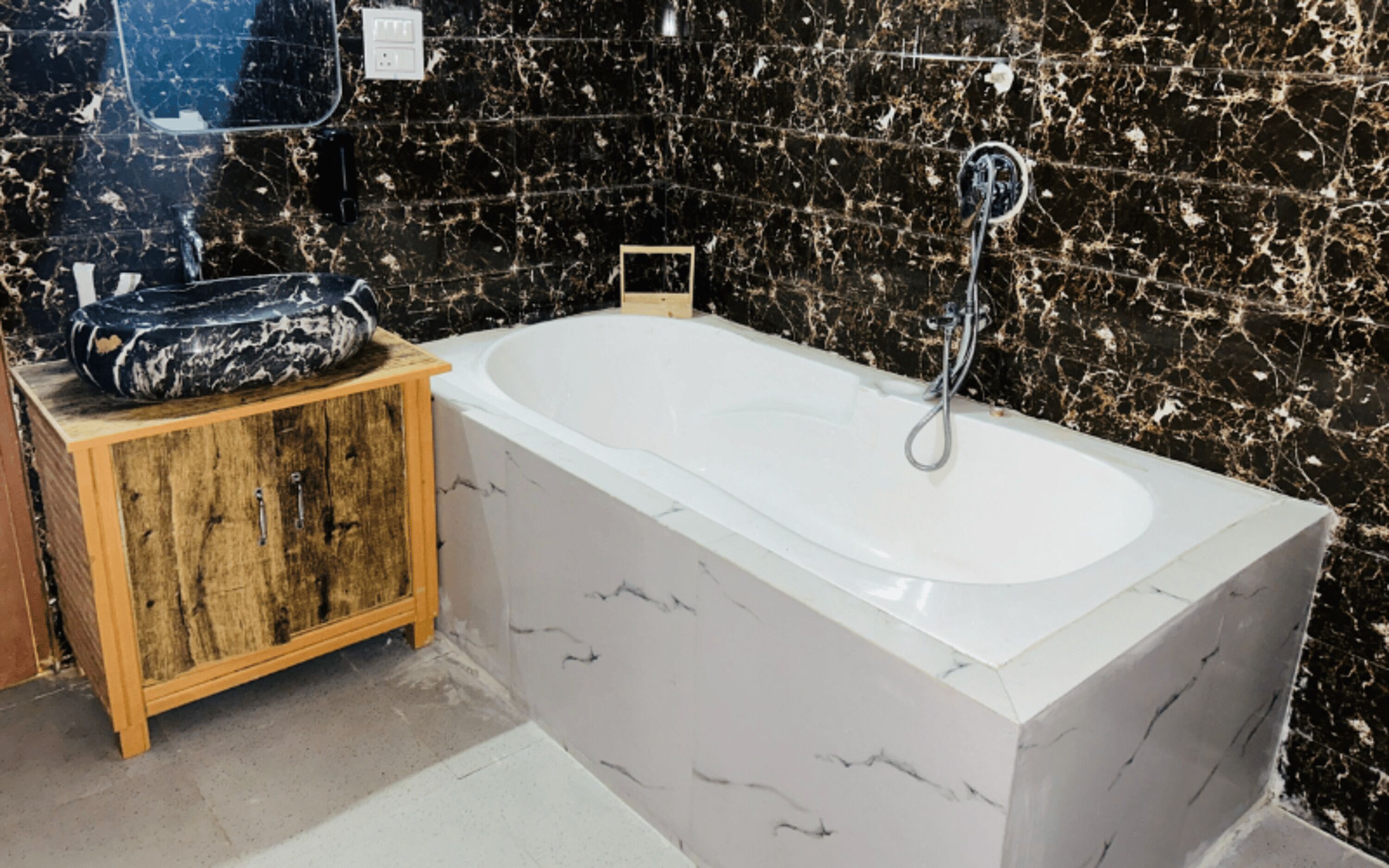 Un baño con una bañera de mármol blanco, un mueble de madera y paredes de mármol negro.