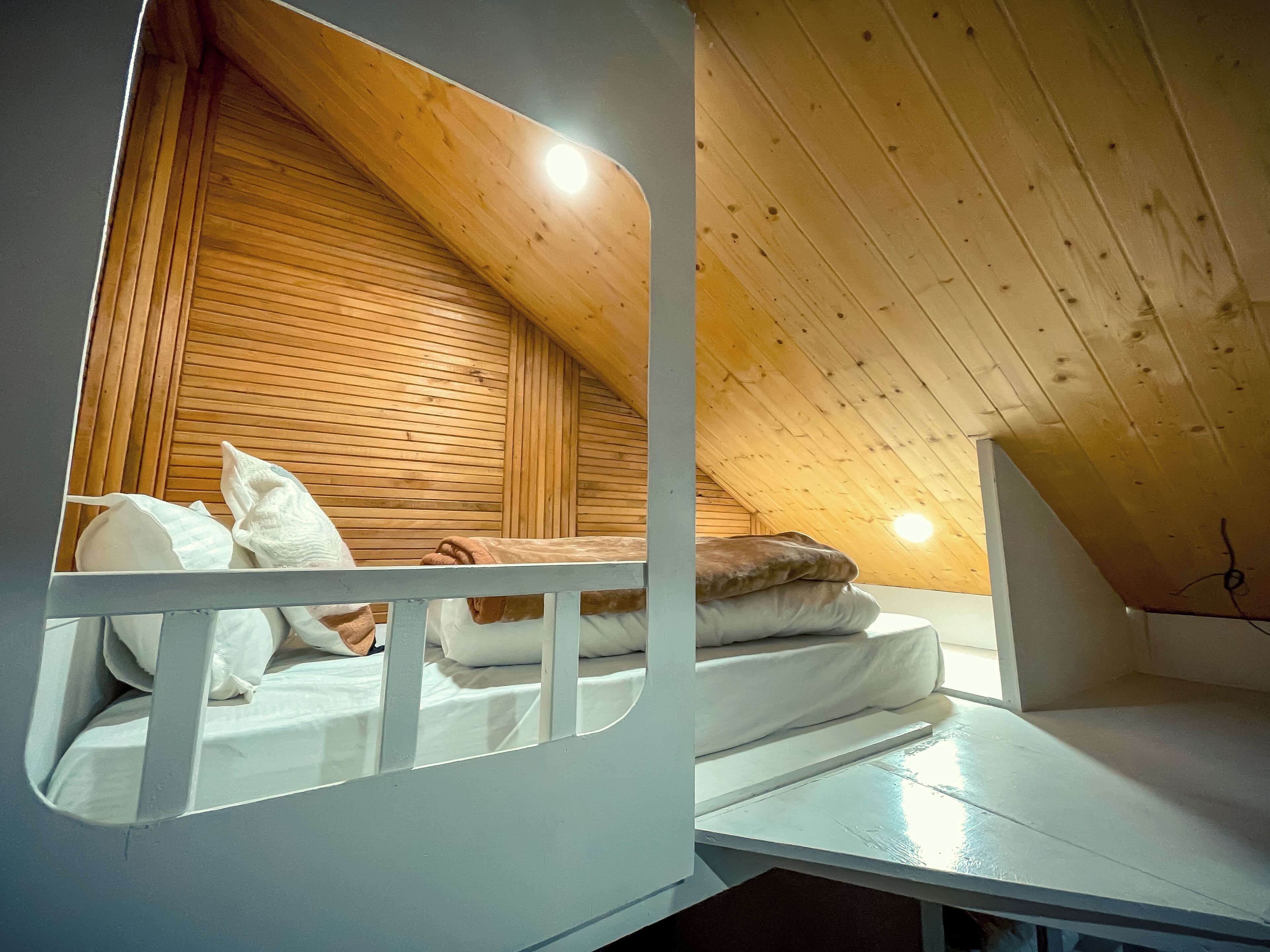 A small, cozy attic bedroom with a sloped ceiling and wooden walls.