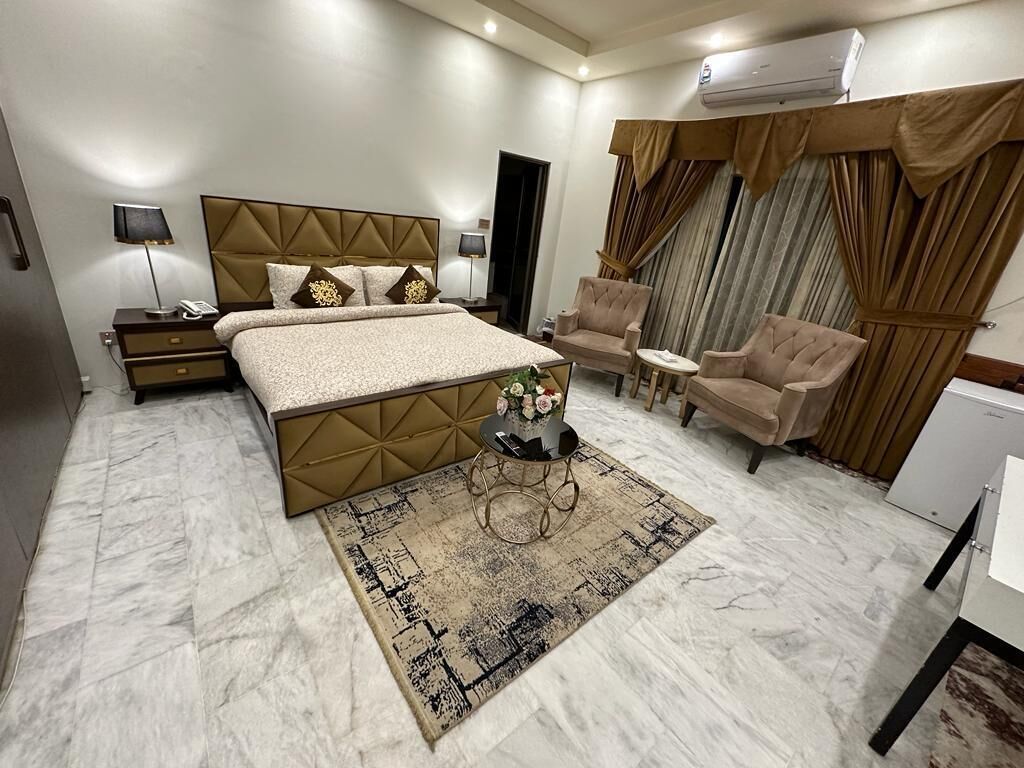 A hotel room with a large bed, two armchairs, a small table, and a desk.