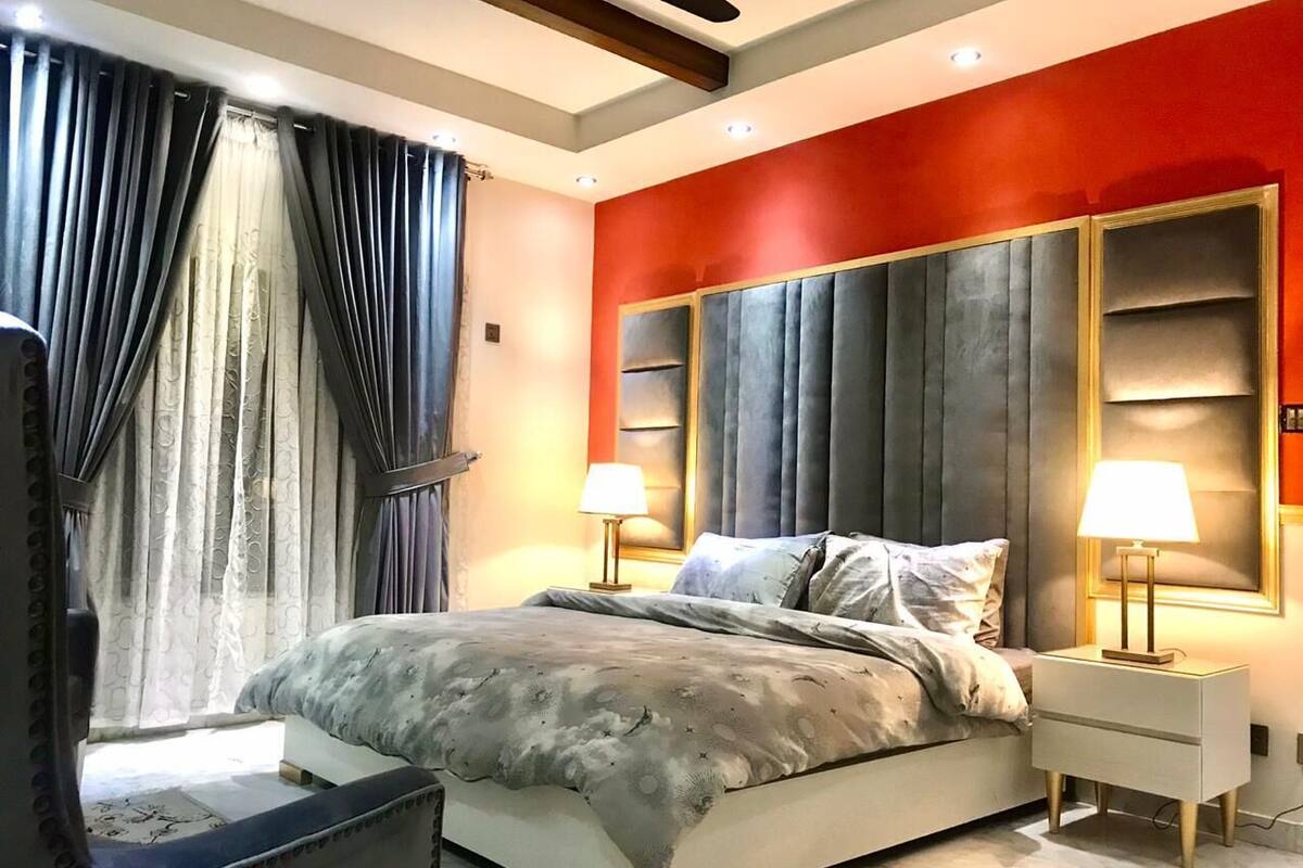 A modern bedroom with a large bed, two bedside tables with lamps, and a mirror.